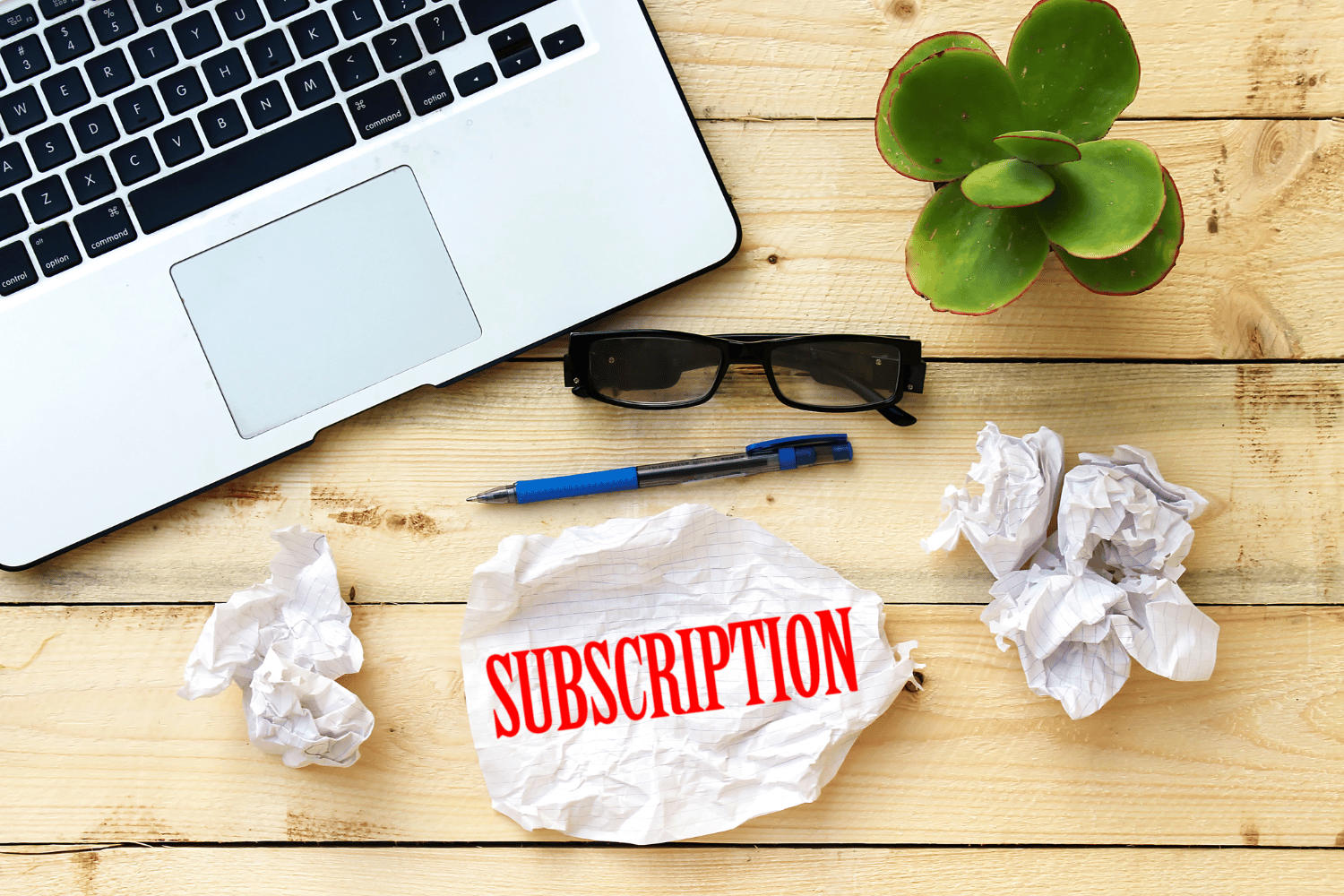 Subscription written on a piece of paper, with a laptop and desk in the background.